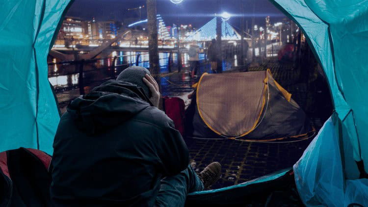 Rethinking the battle against homelessness homeless person in tent amid bright lights of city