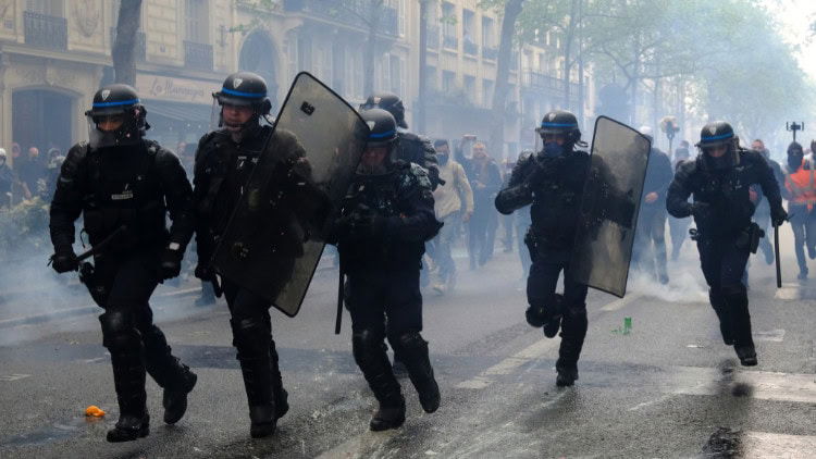 Europe: world leader in eroding workers’ rights riot police with shields running on the street, gas in the air