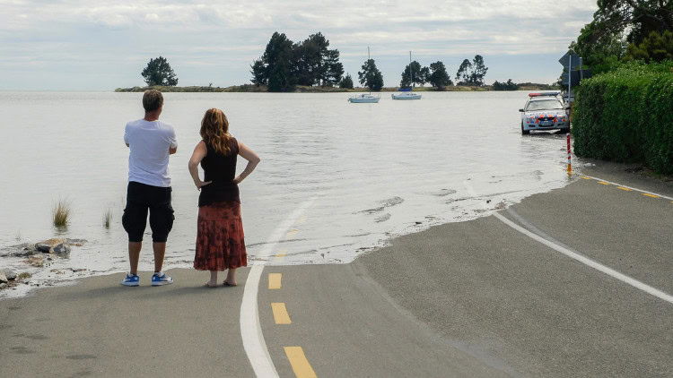 Rising tides, sinking boats: growth, climate and justice two people observing road cut off by rising water level