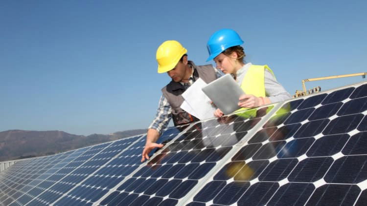 The young generation needs quality traineeships Man training young woman, both in safety helmets, on installation of solar panels