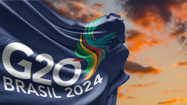 Taxing the super-rich—more possible than ever Flag with G20 Brasil 2024 on it against backdrop of reddish sky