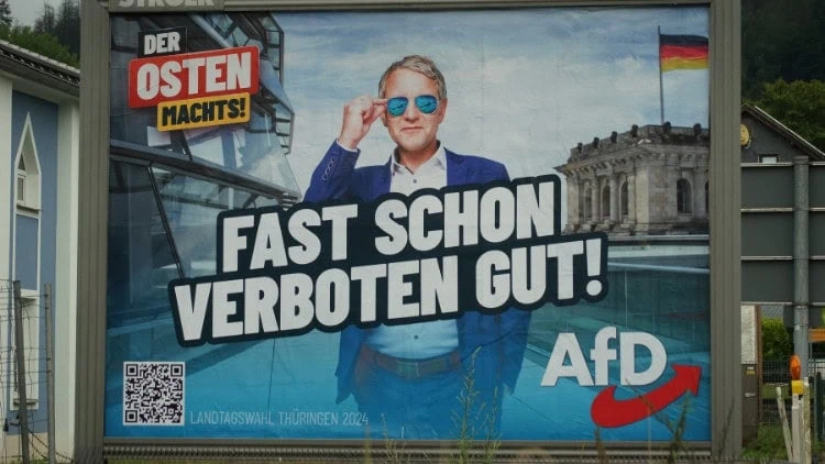 The AfD can win on an extremist platform Man in sunglasses on AfD election poster, saying 'Der Osten machts!' and 'fast schon verboten gut!