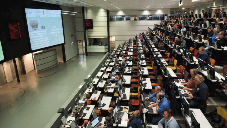 The canker among Europe’s roses Auditorium with audience facing big screen with details of batch of flowers on sale