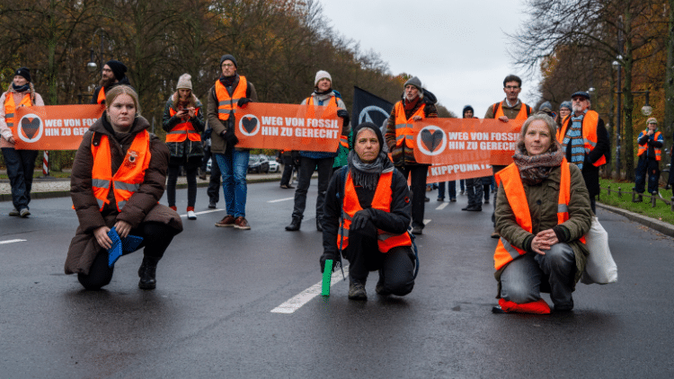Criminalising climate protest while ignoring the crisis demonstrators who have taken over a street wearing high-visibilty jackets and carrying anti-fossil-fuel banners