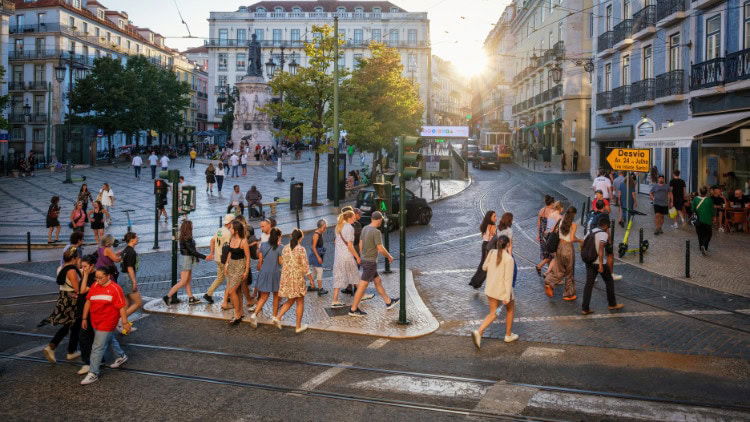 In difficult times, social cohesion has improved people crossing square in Lisbon at sunset