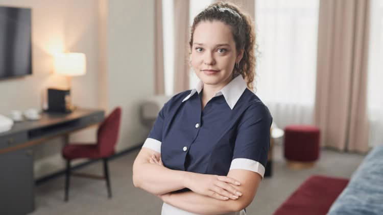 Sub-minimum wages: young people, old attitudes cleaning worker in hotel room facing camera